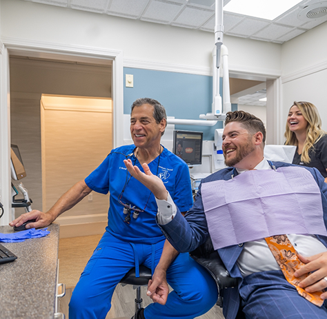 Dentist sitting next to patient and checking computer