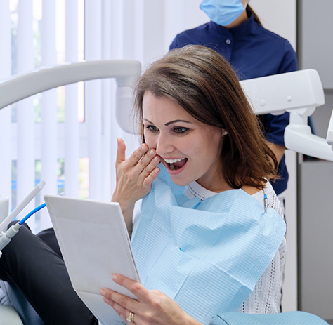 Female patient checking smile in mirror after smile makeover