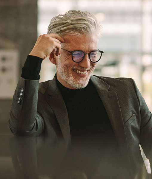 Older man with white hair and glasses smiling