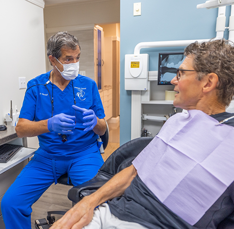 Dentist with mask explaining treatment to patient