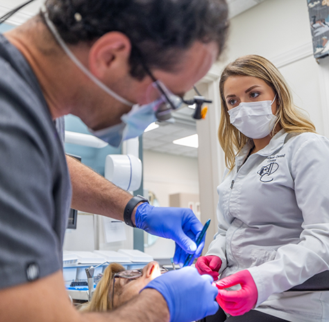 Dental team member watching dentist treat patient