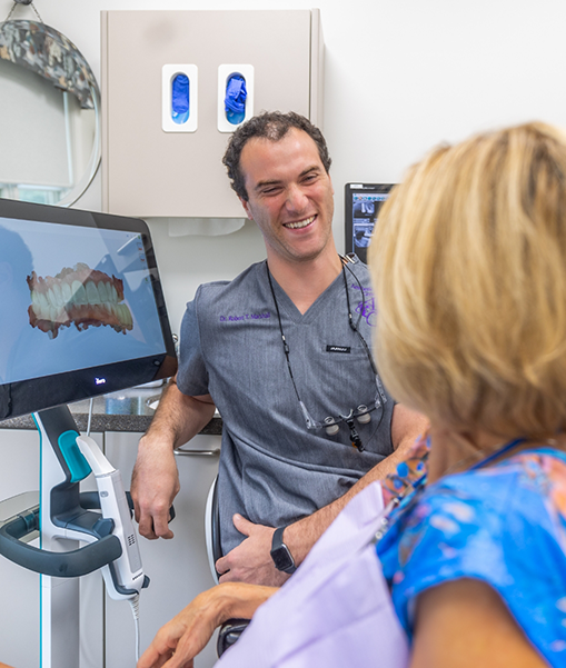 Male dentist talking to female dental patient