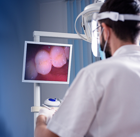 Male dentist looking at image of teeth taken by intraoral camera