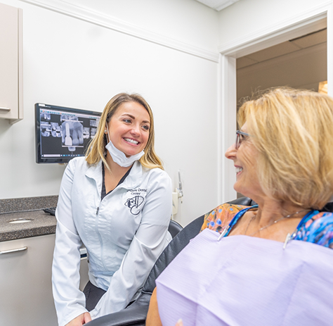 Dental team member sitting next to patient and smiling at them