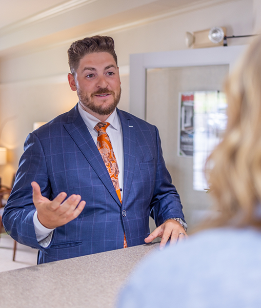 Man in suit talking to patient at reception desk