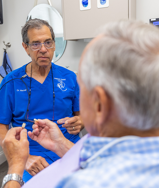 Dentist in Concord talking to male patient viewed from behind