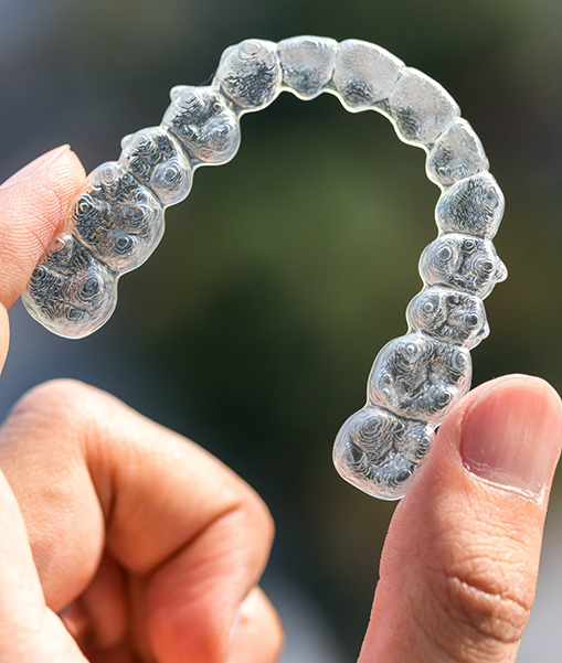 Close-up of hand holding Invisalign clear aligner in Concord