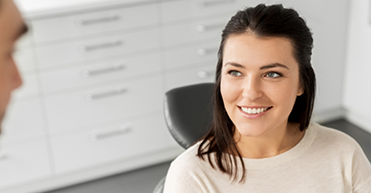 Woman in white shirt looking up at dentist and smiling