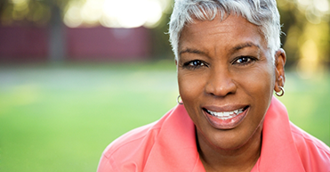 Woman in pink shirt outside smiling