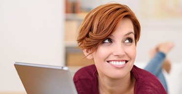 Red haired woman holding tablet smiling