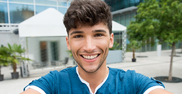 Man in blue shirt smiling in front of hotel