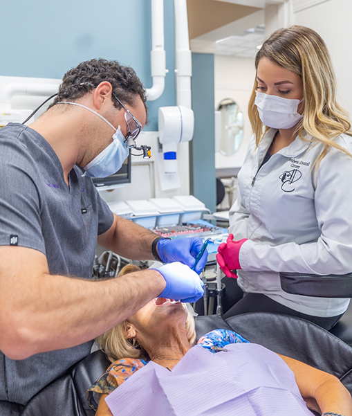 Dentist and team member with masks giving patient preventive dentistry in Concord