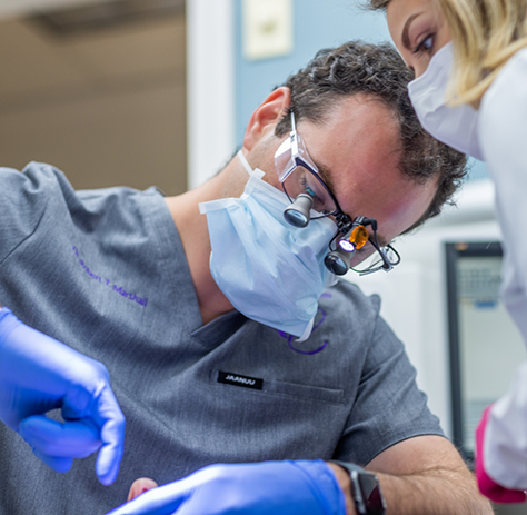 Dentist with magnifying glasses treating a patient