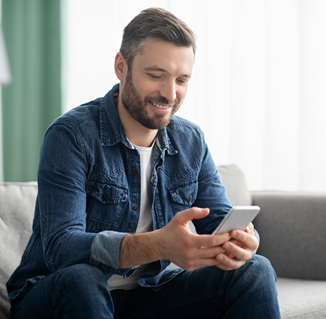 Man sitting on couch looking at cell phone