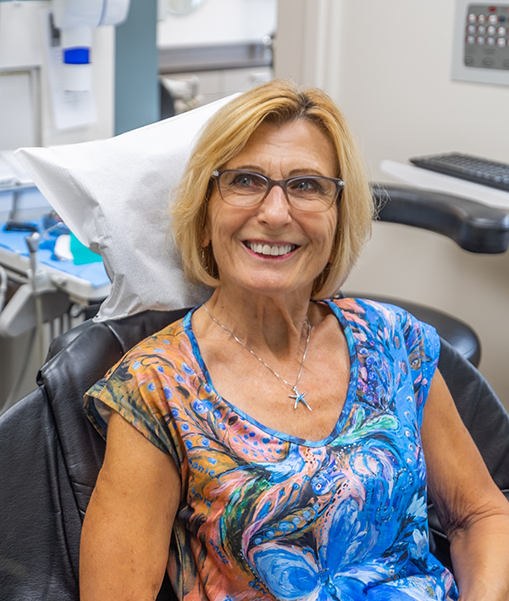 Senior woman with glasses sitting in dental chair and smiling